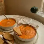 creamy vegan tomato and cauliflower bisque in a bowl with bread