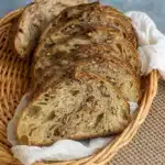 Maple Pecan Sourdough Bread loaf cooling on wooden board with pecans