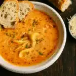 tomato tortellini soup in rustic bowl with Parmesan and basil