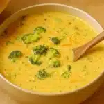 Bowl of Cheesy Broccoli Cheddar Soup topped with melted cheese and fresh broccoli