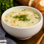 creamy pioneer woman potato soup in white bowl with parsley and bread