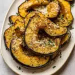 Irresistible Herb-Roasted Acorn Squash With Parmesan served on rustic plate