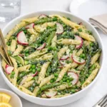 A large bowl of creamy Asparagus Pasta Salad with lemon and herbs.