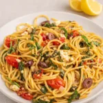 Greek Spaghetti with feta, olives, and tomatoes on rustic table