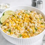 Healthy Mexican Street Corn Pasta Salad in a white bowl with lime wedges.