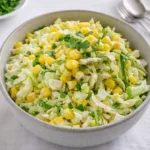 A vibrant bowl of Jalapeno Corn Coleslaw on a rustic table
