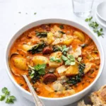 A bowl of Smoky Potato and Kale Soup with chorizo and crusty bread.