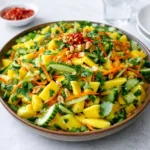 A vibrant Thai Mango Salad in a rustic bowl with fresh herbs and peanuts.