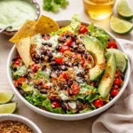 30 Minute Loaded Quinoa Taco Salad in a ceramic bowl with avocado and dressing.