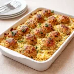 A bowl of Greek Chicken Meatballs with Lemon Orzo garnished with feta and herbs.