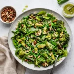 A vibrant green vegan salad with quinoa and roasted vegetables on a platter.