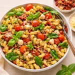 Vibrant Sun-Dried Tomato Pasta Salad in a large serving bowl on a rustic table.