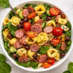 A vibrant bowl of Tortellini Pasta Salad with fresh vegetables and herbs